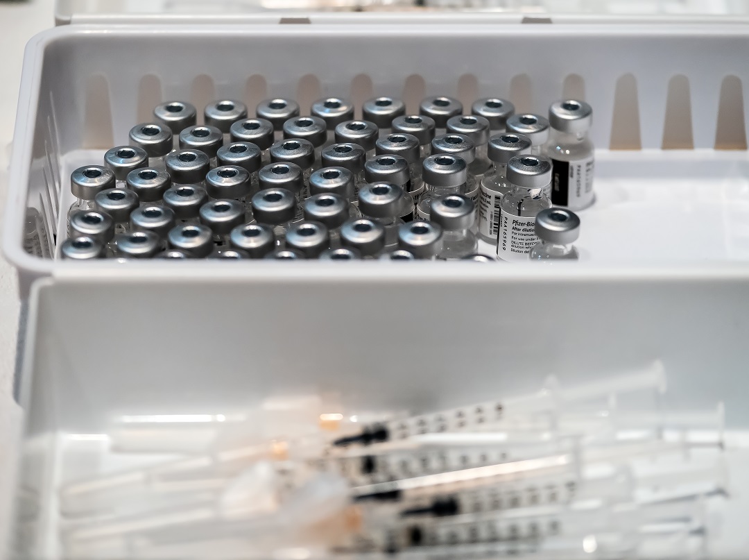 A white basket filled with silver-topped vaccine viles and another white basket of syringes.